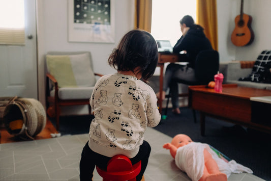 Une maman tient son bébé dans les bras tout en travaillant à la maison