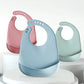 Trois bavoirs bébé en silicone rose, bleu et vert sauge
