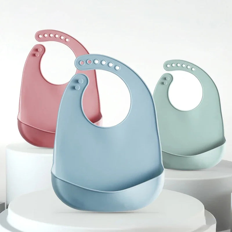 Trois bavoirs bébé en silicone rose, bleu et vert sauge